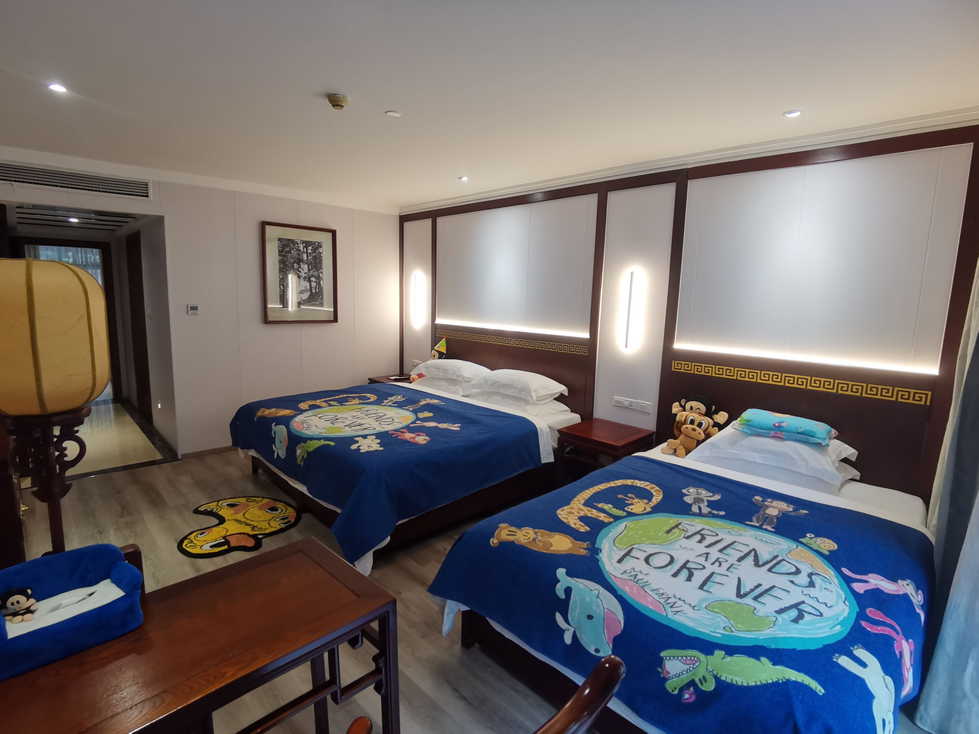 Una habitació d'hotel amb dos llits, cadascun amb un estovat blau que presenta personatges de dibuixos animats i el text 
