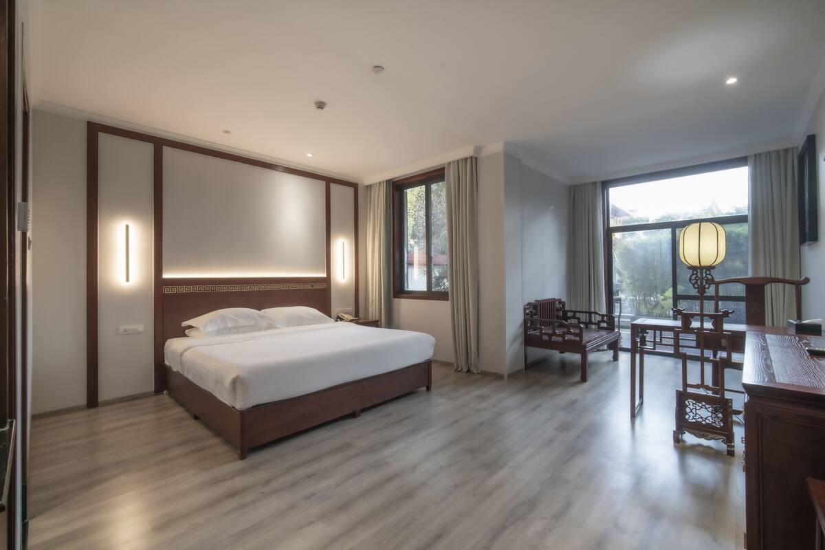 A hotel room with a large bed, wooden furniture, and a view of the outdoors.