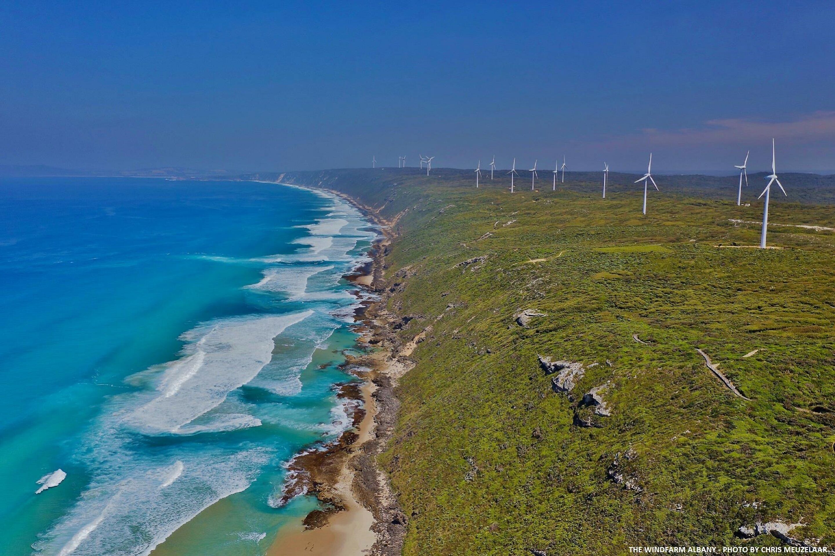 Un paysage côtier avec des éoliennes et une plage.
