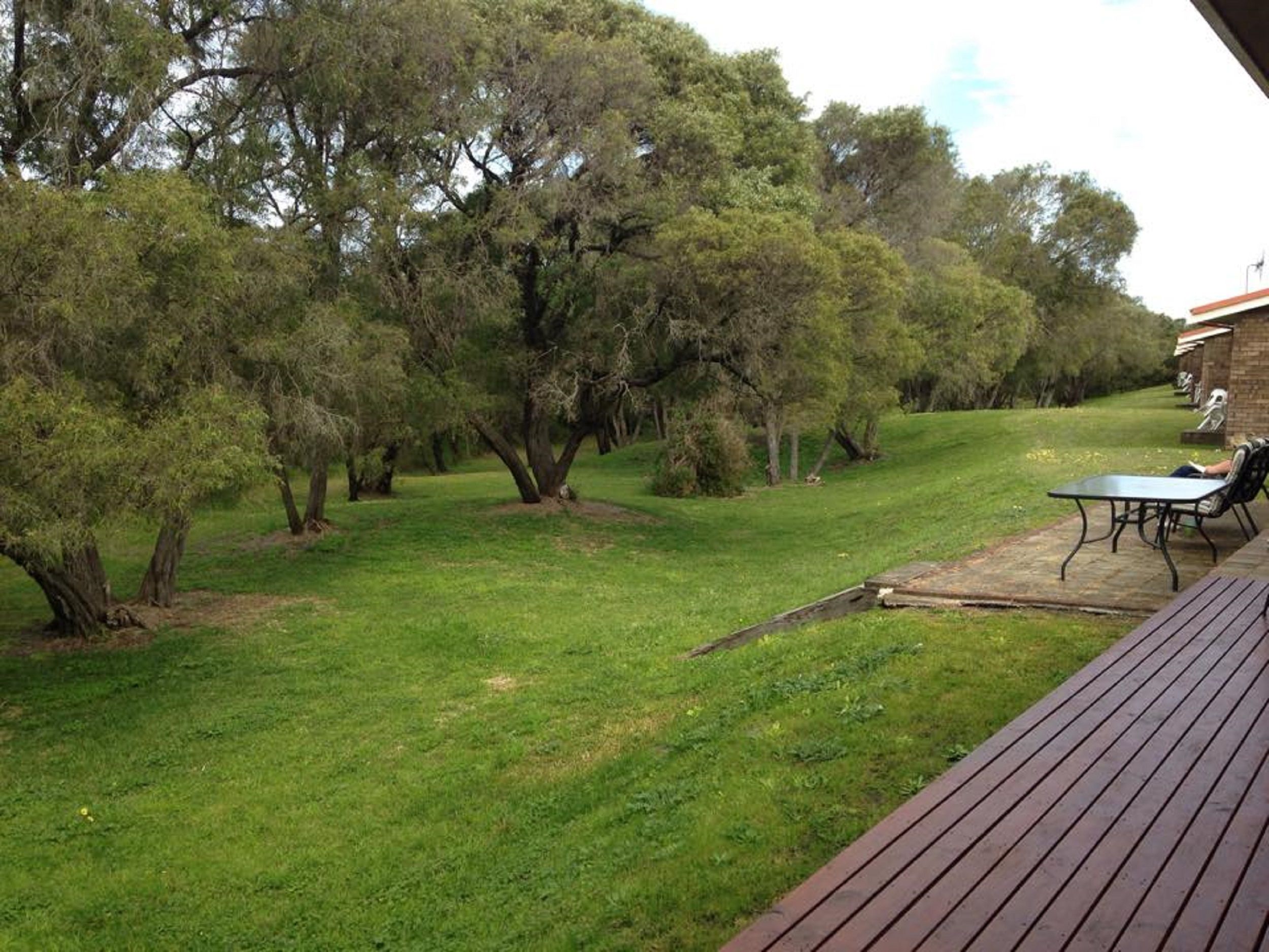 A backyard with a wooden deck, a table, and chairs.