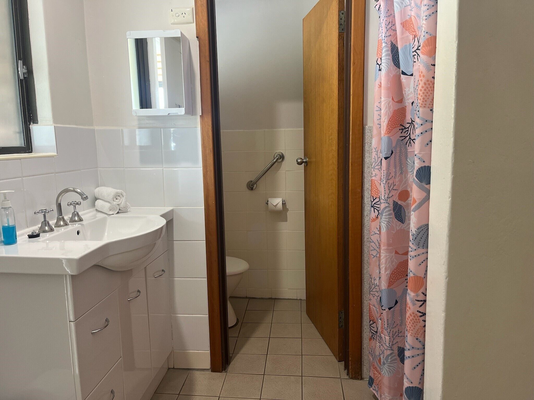 A bathroom with a sink, two faucets, a mirror, a toilet, and a shower door.