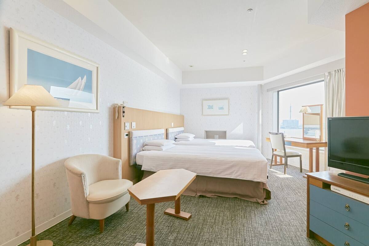 Una habitación de hotel con cama, escritorio, silla, televisor y lámpara.