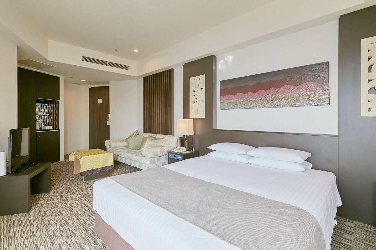 Una habitación de hotel con una cama grande, un sofá, un televisor y un escritorio.