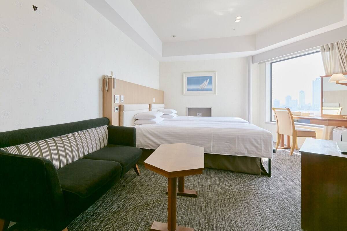 Una habitación de hotel con una cama, un sofá, un escritorio y una silla.