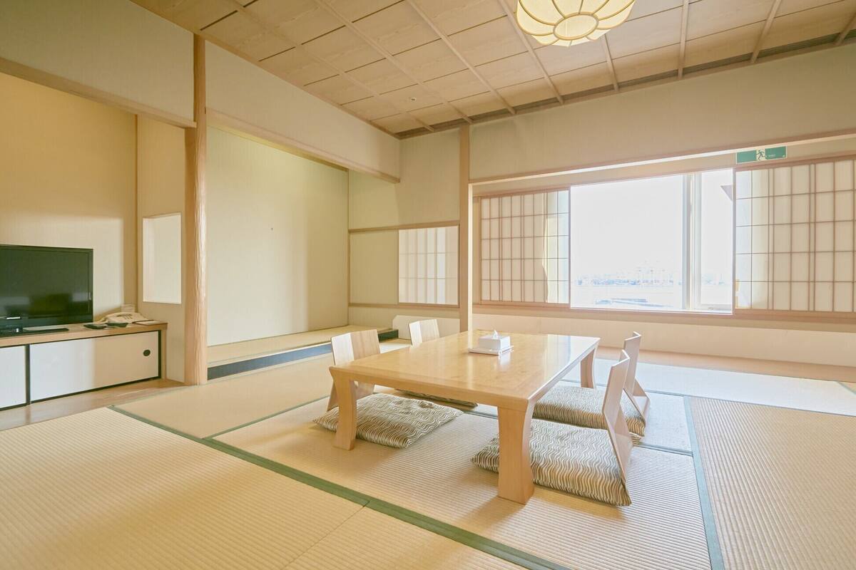 Una habitación tradicional japonesa con suelo de tatami, una mesa baja y puertas correderas shoji.