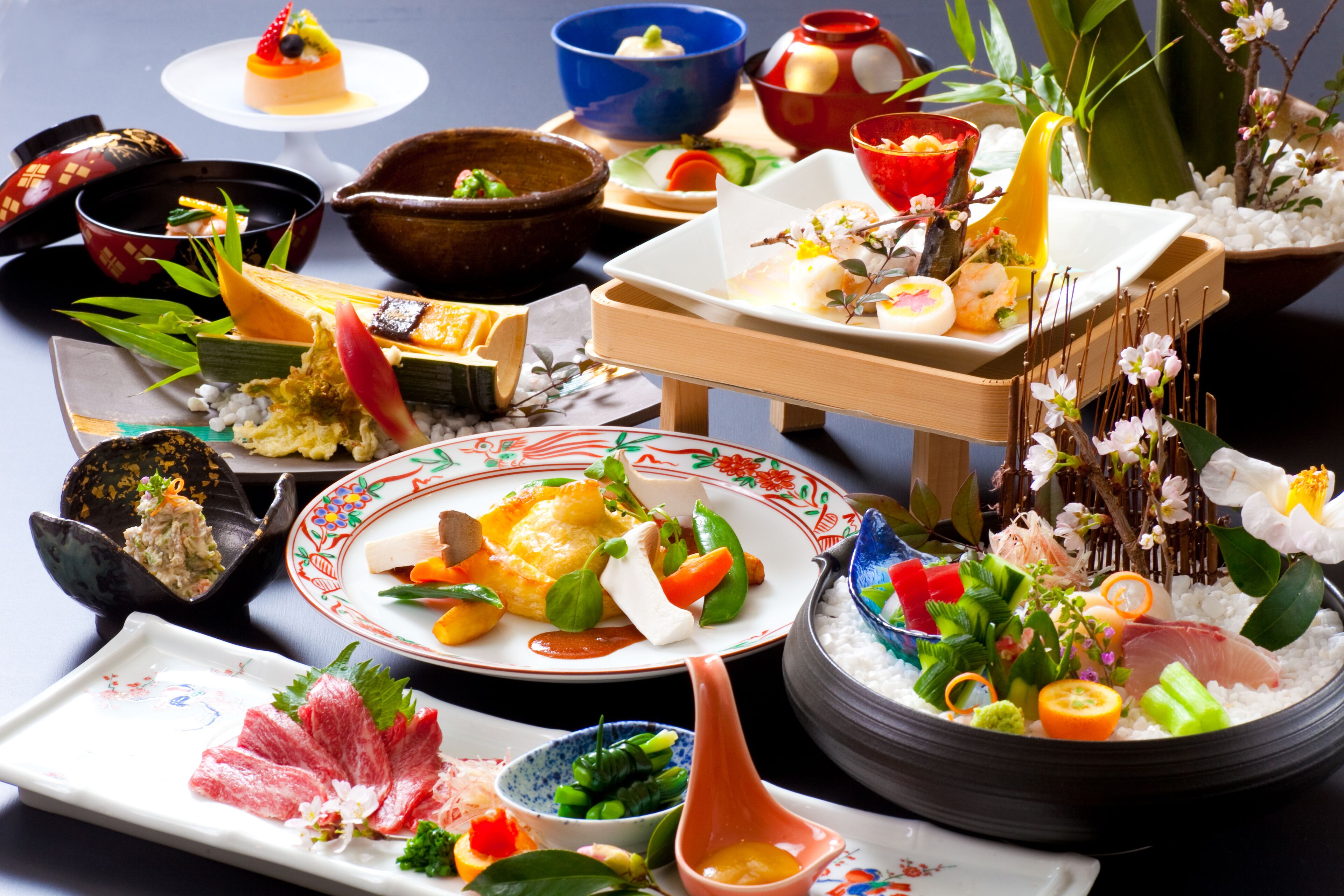 A variety of dishes on a table, including sushi, sashimi, and other Asian cuisine.