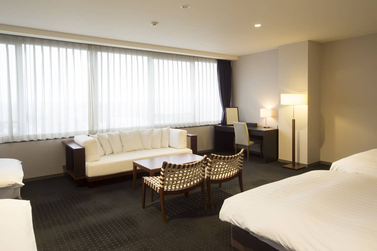 Una habitación de hotel con cama, sofá, escritorio y dos sillas.