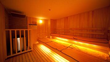 A sauna room with wooden benches and a glass partition.