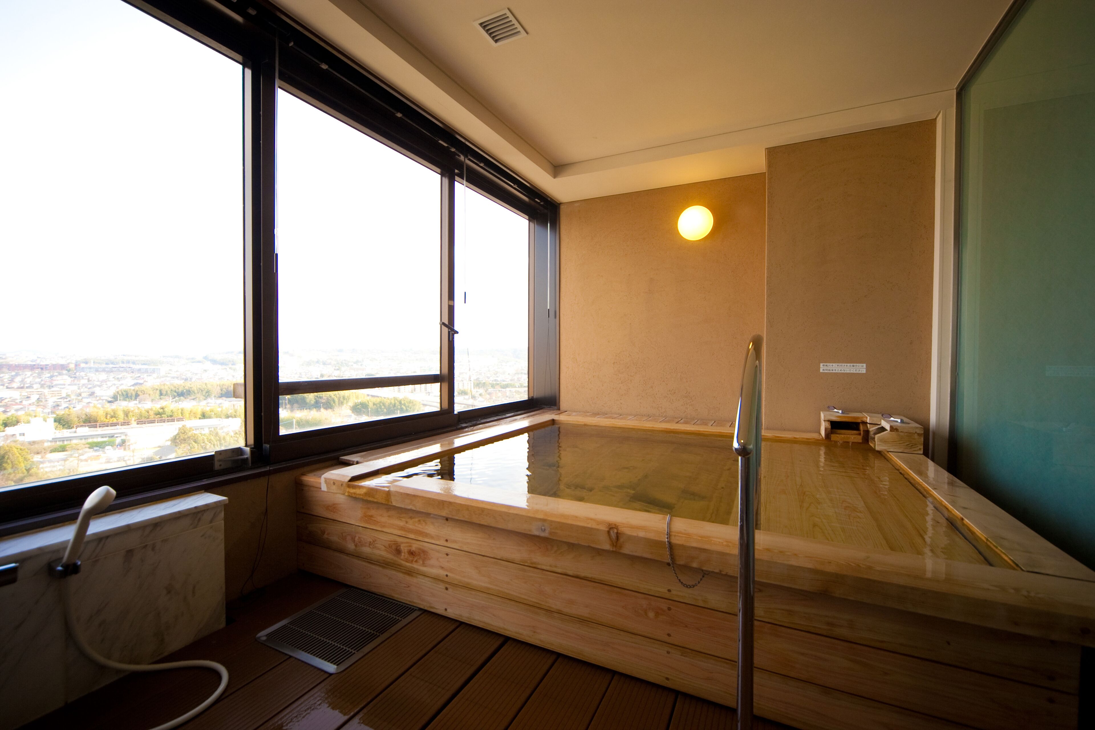A wooden hot tub with a view of a cityscape through large windows.