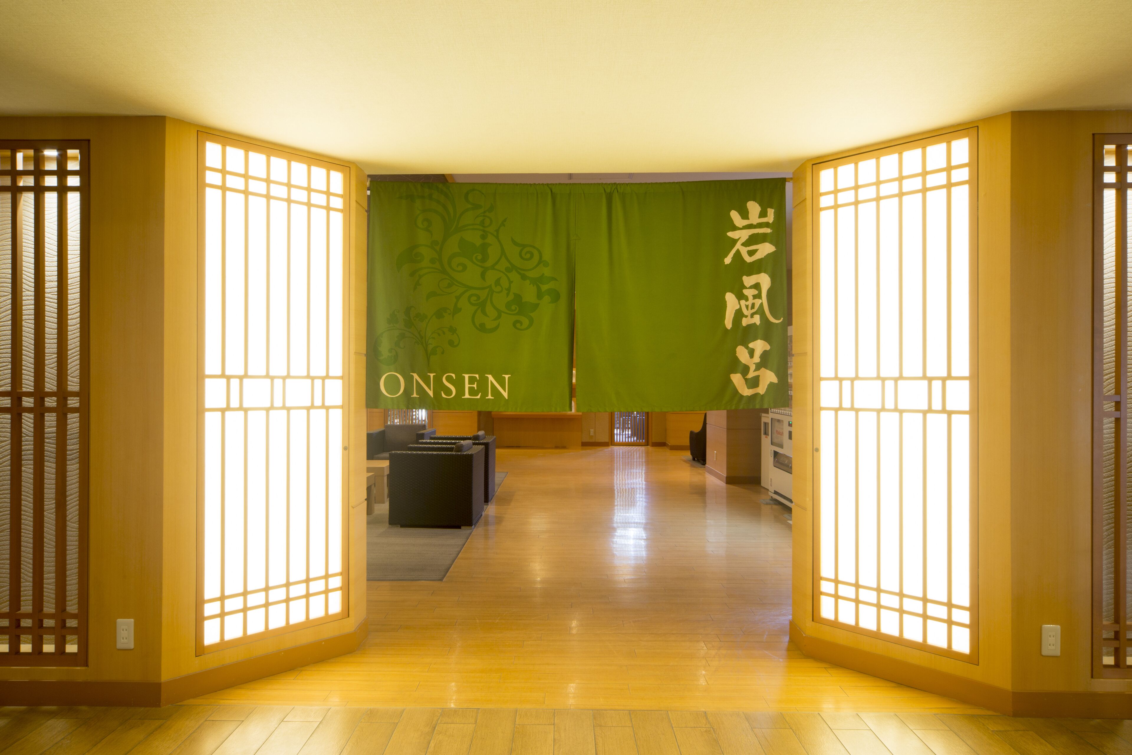 A traditional Japanese interior with sliding doors, a reception desk, and a green wall with kanji characters.