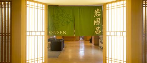 A traditional Japanese interior with sliding doors, a reception desk, and a green wall with kanji characters.