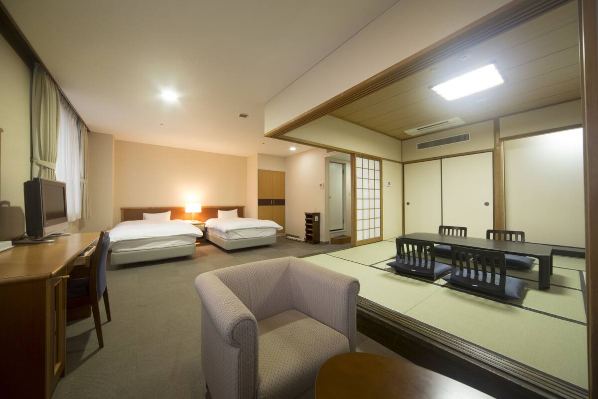 Una habitación de hotel con cama, escritorio, silla y una mesa de comedor con sillas.