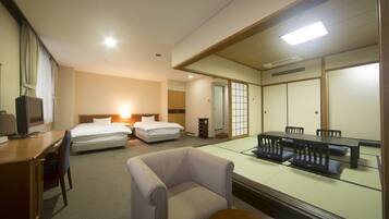 A hotel room with a bed, desk, chair, and a dining table with chairs.