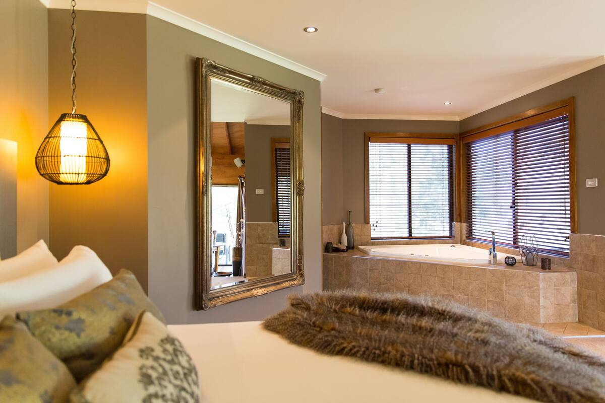 A modern bathroom with a large mirror, a bathtub, and a shower area.