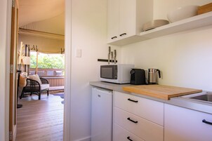 Una cocina con armarios blancos, un microondas, un tostador y una tabla de cortar de madera.