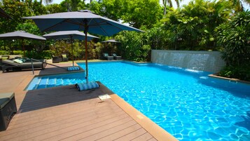Una piscina al aire libre, sombrillas, sillones reclinables de piscina