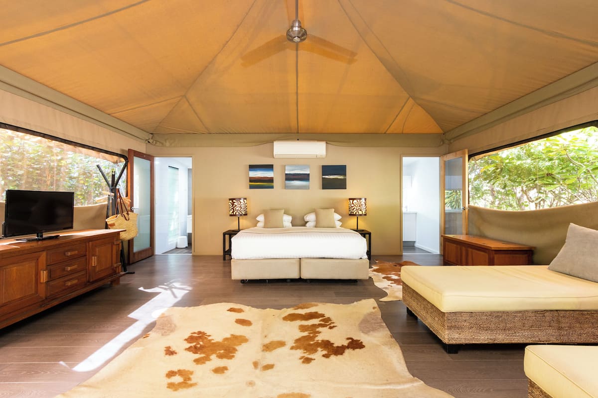 A bedroom with a bed, a TV, a wooden dresser, and a cowhide rug.