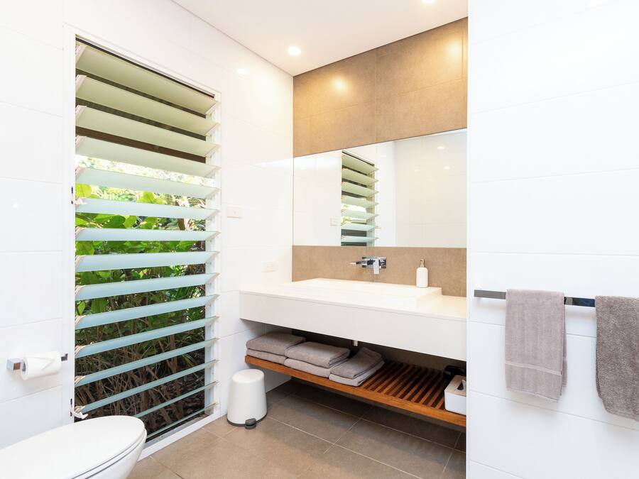 A modern bathroom with a white sink, mirror, and towel rack.