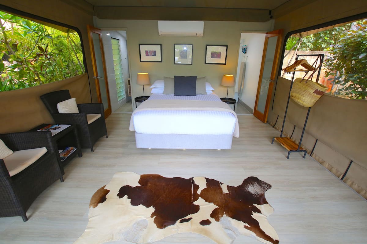 A bedroom with a large bed, two bedside tables with lamps, a sofa, and a cowhide rug.