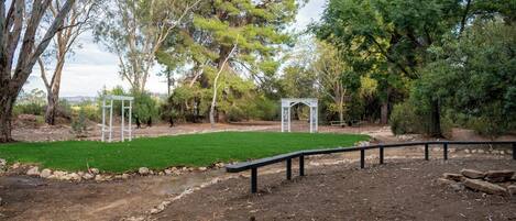 A park with a dirt path, a white gazebo, and a bench.