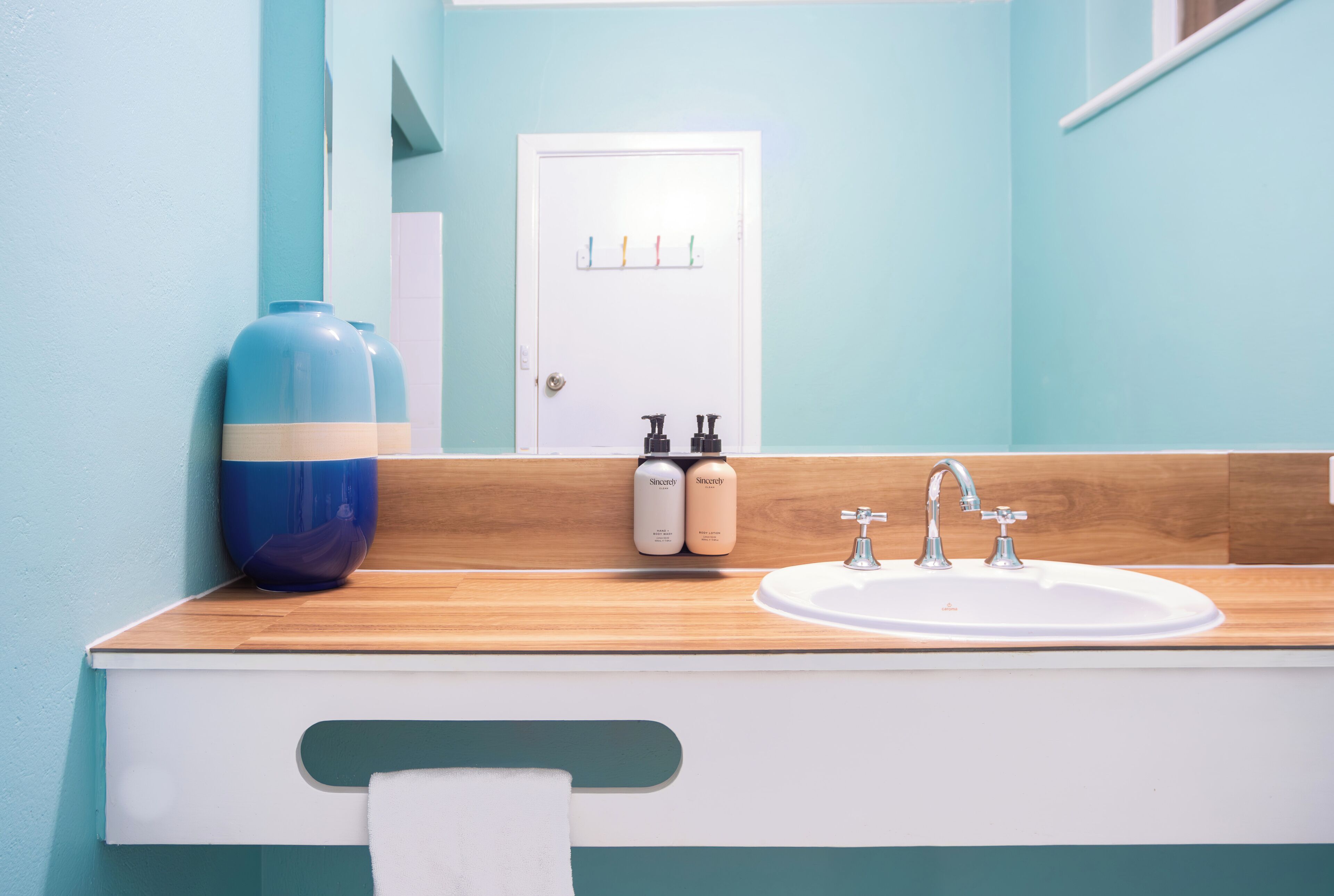 A bathroom with a wooden countertop, a sink, and two bottles of skincare products.