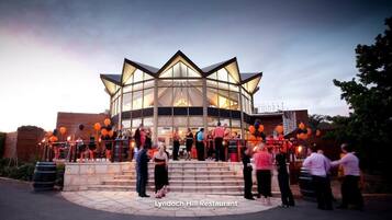 The exterior of Lyndoch Hill Restaurant with a modern glass facade and a circular seating area.