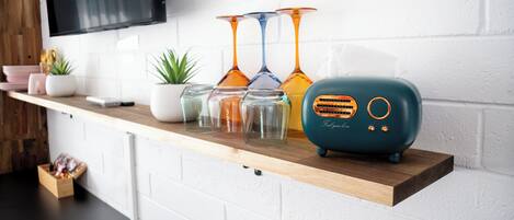 Una encimera de cocina con una radio color turquesa, cristalería y una planta en maceta.