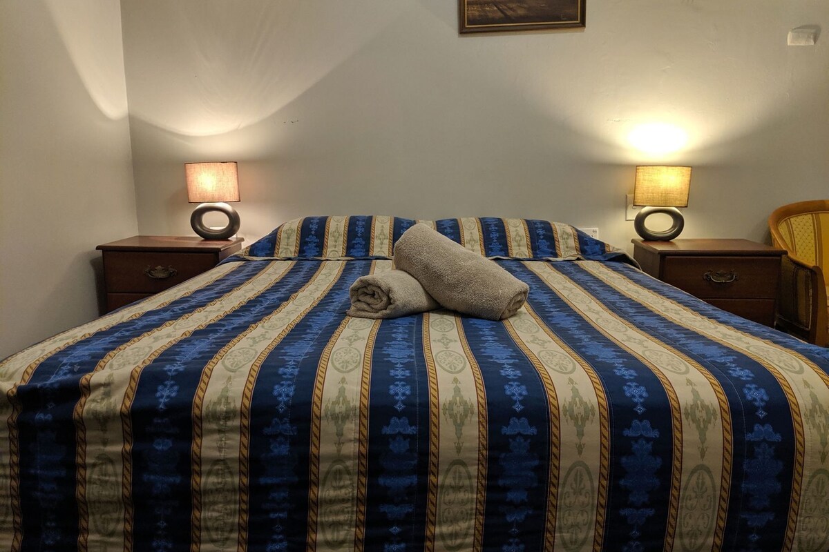 A neatly made bed with striped bedding, two bedside lamps, and a framed picture on the wall.