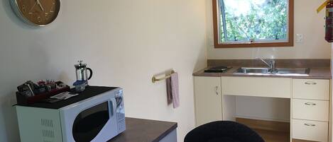 A compact kitchen with a microwave, a sink, and a window with a view of greenery.