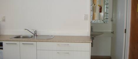 Una cocina con un lavamanos, armarios y un reloj de pared.