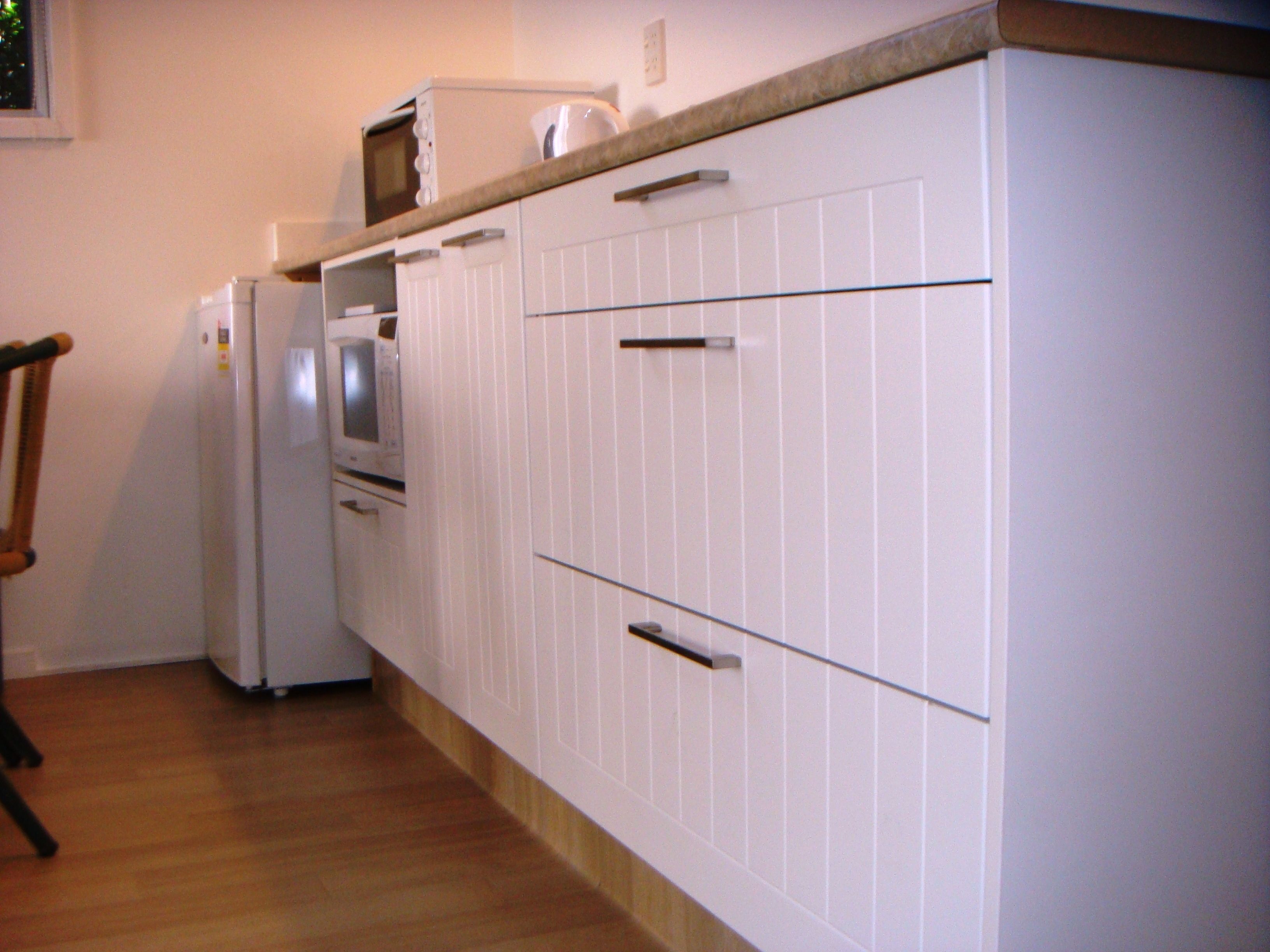 A kitchen with white cabinets, a microwave, and a refrigerator.