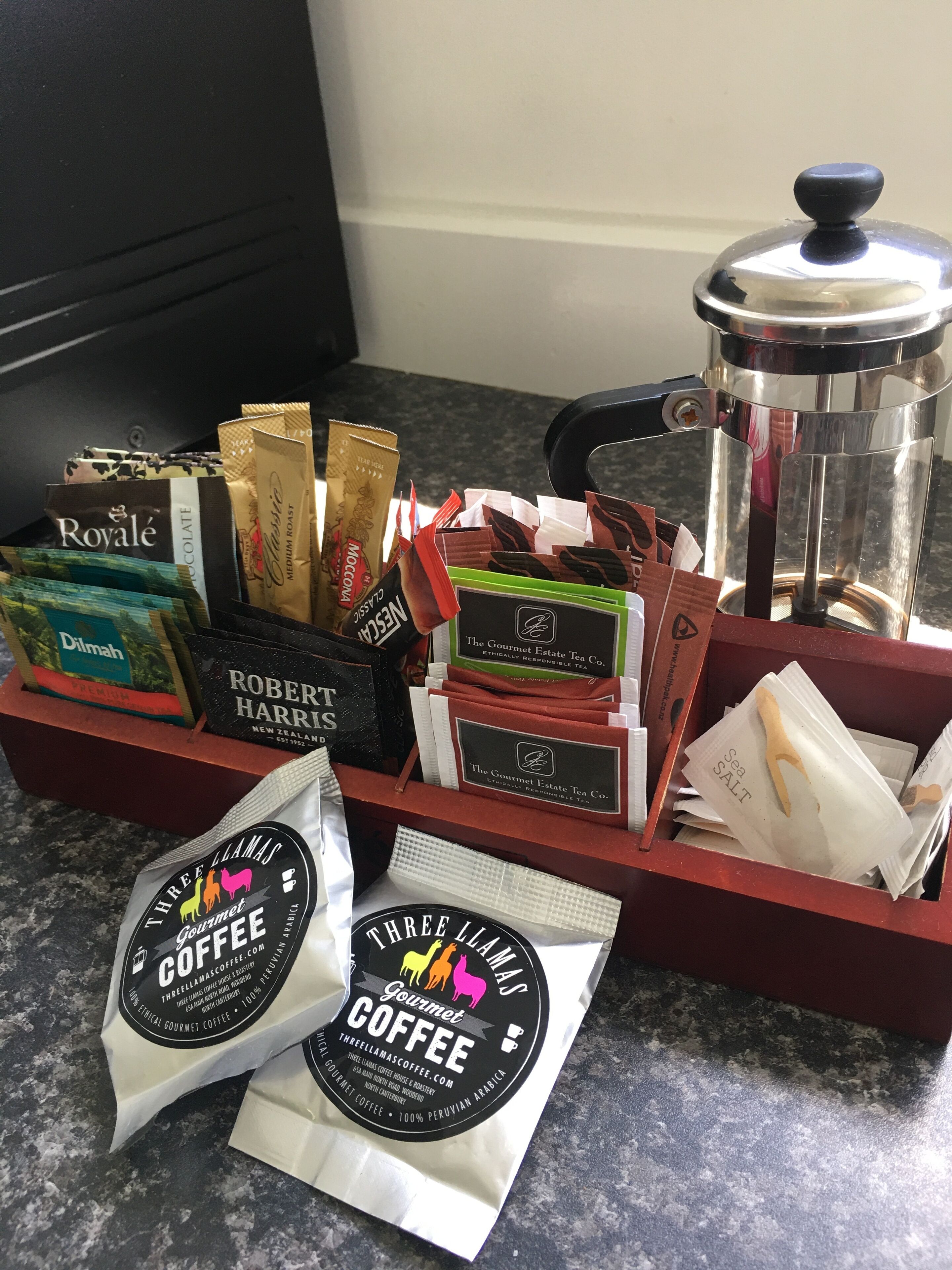 A coffee station with various coffee bags and a French press.