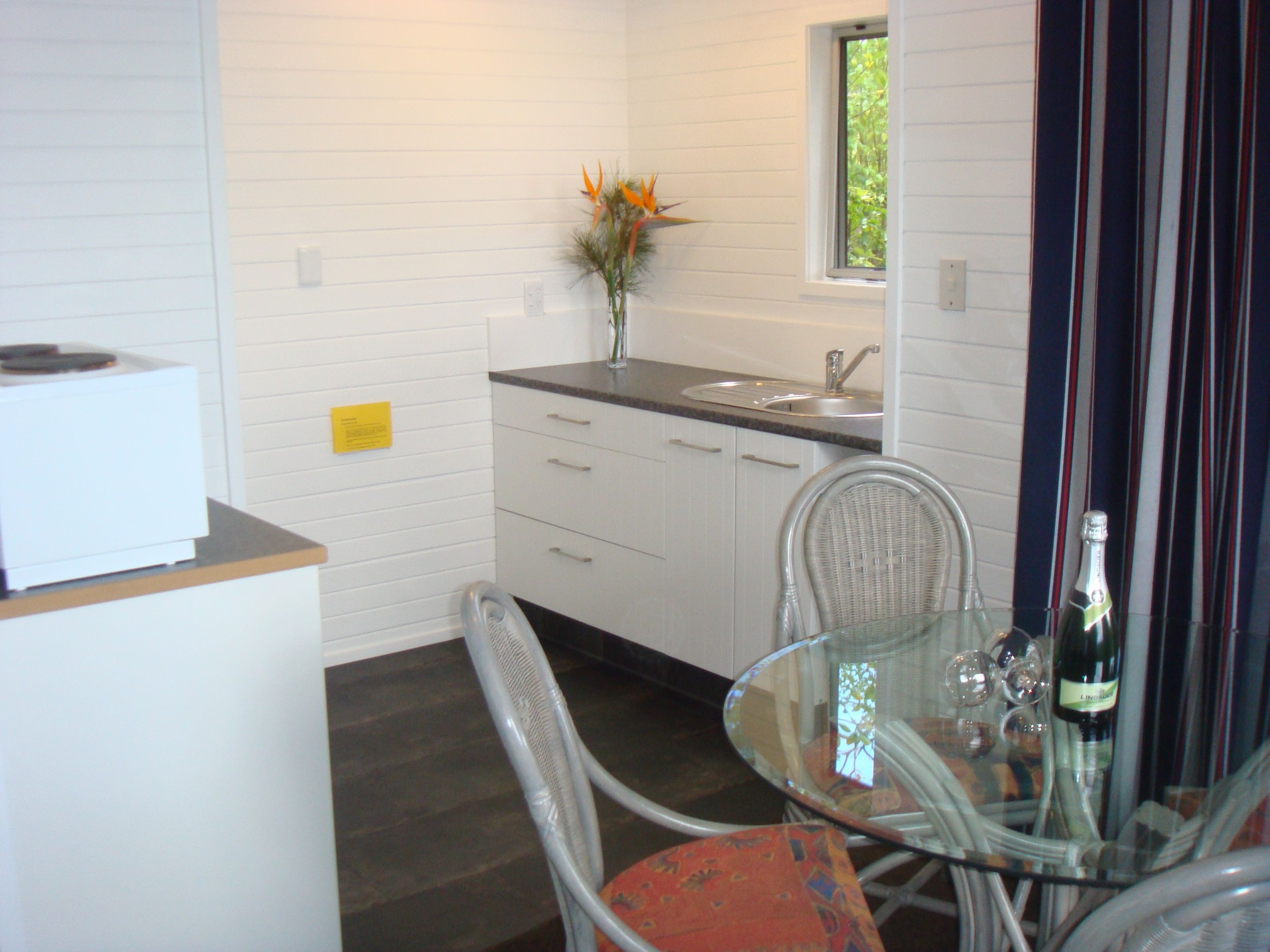 A modern kitchen with white cabinetry, a built-in sink, and a dining area with a glass table and chairs.