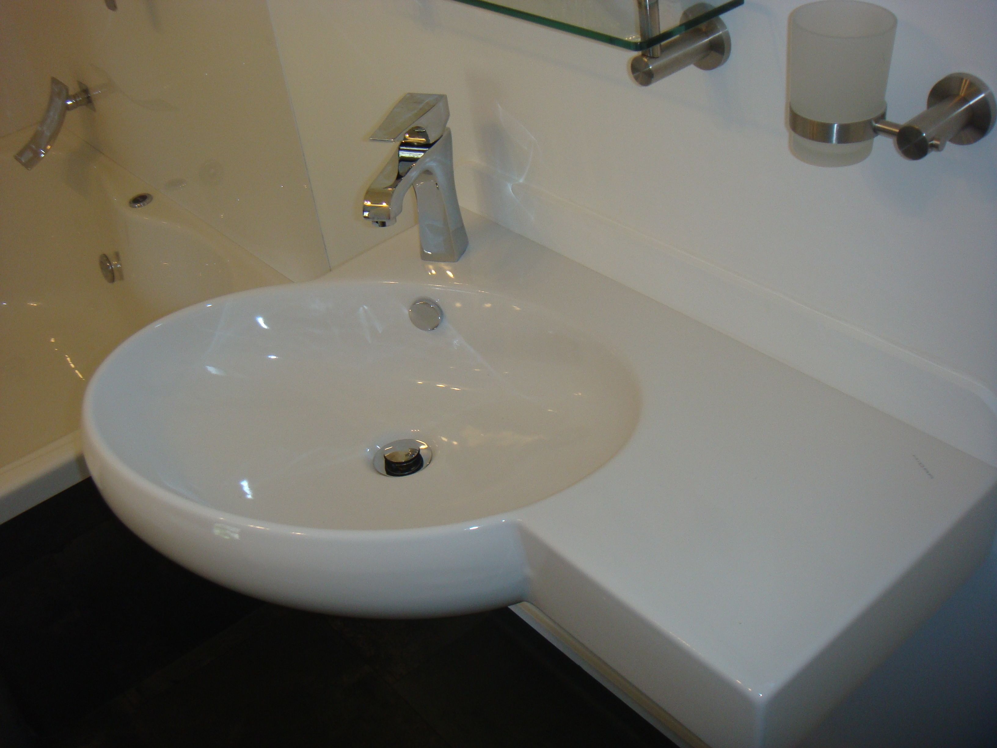 Un lavabo blanc pour la salle de bain, doté d’un robinet chromé, d’un distributeur de savon en verre et de toilettes blanches.