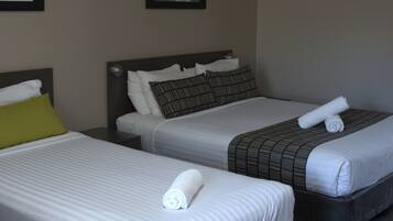 Two adjacent hotel beds with white linens, pillows, and rolled towels.