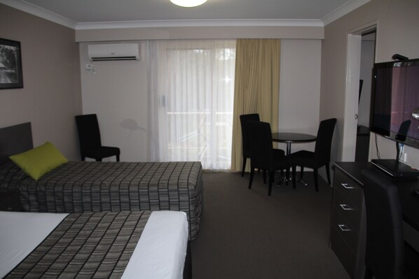 A hotel room with a bed, a desk, and a television. - Galaxy Motel (West Gosford)