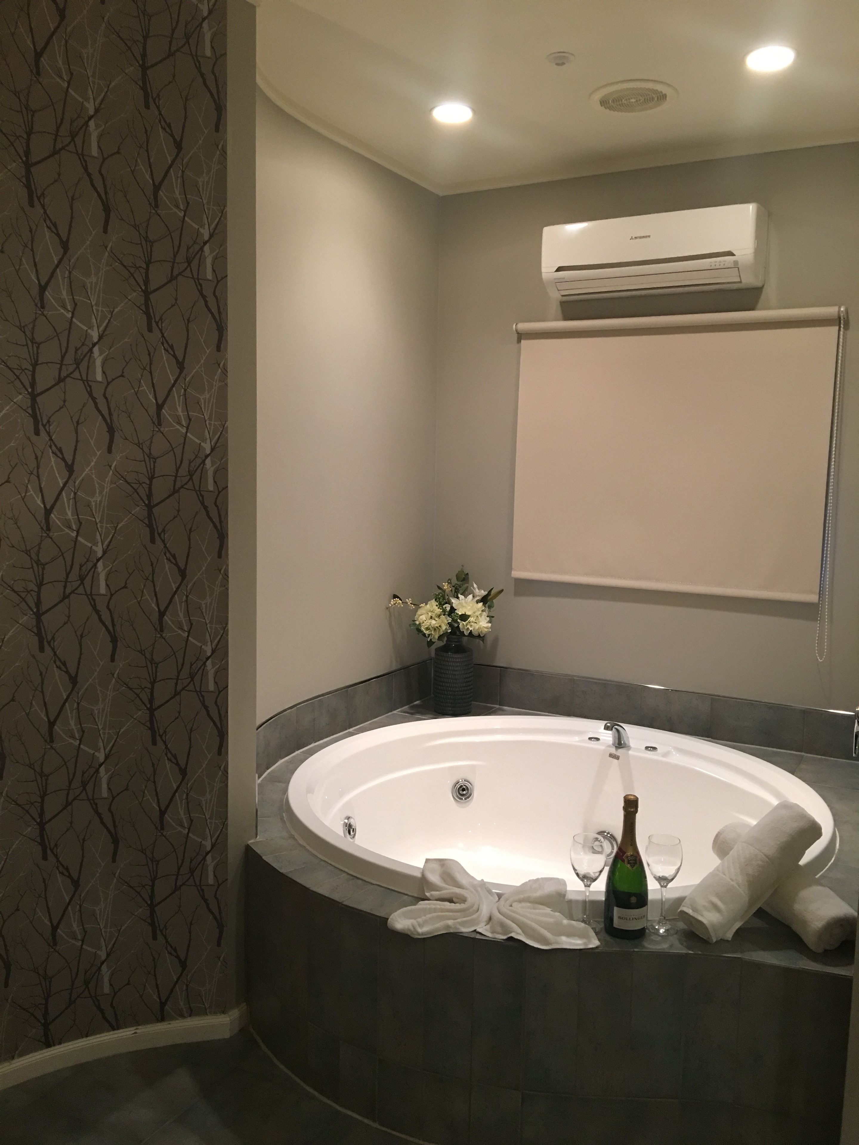 Ein modernes Badezimmer mit einer freistehenden Badewanne, einer Wand-Klimaanlage und einer Vase mit Blumen.