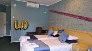 A hotel room with two beds, a wall-mounted air conditioner, and a decorative banner.