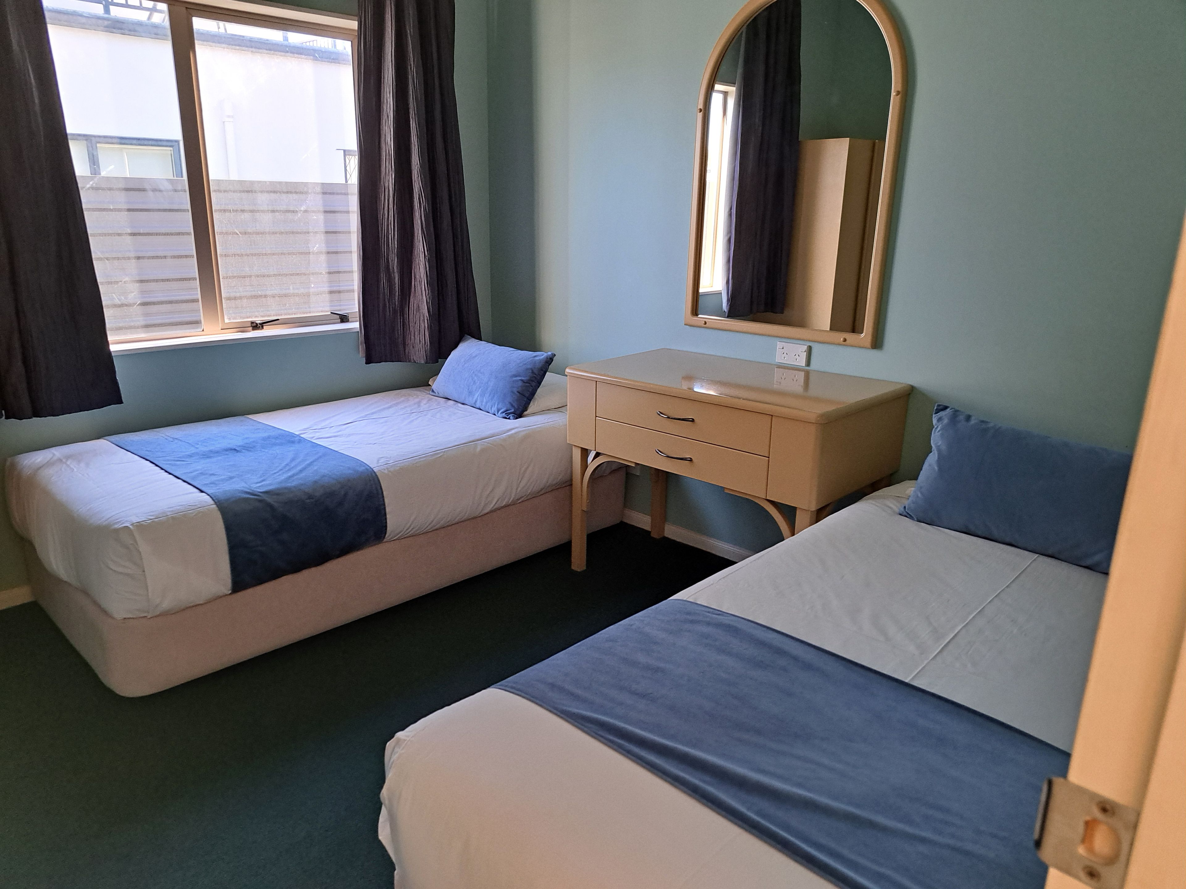 Un dormitorio con dos camas, un aparador, un espejo y una ventana con cortinas.