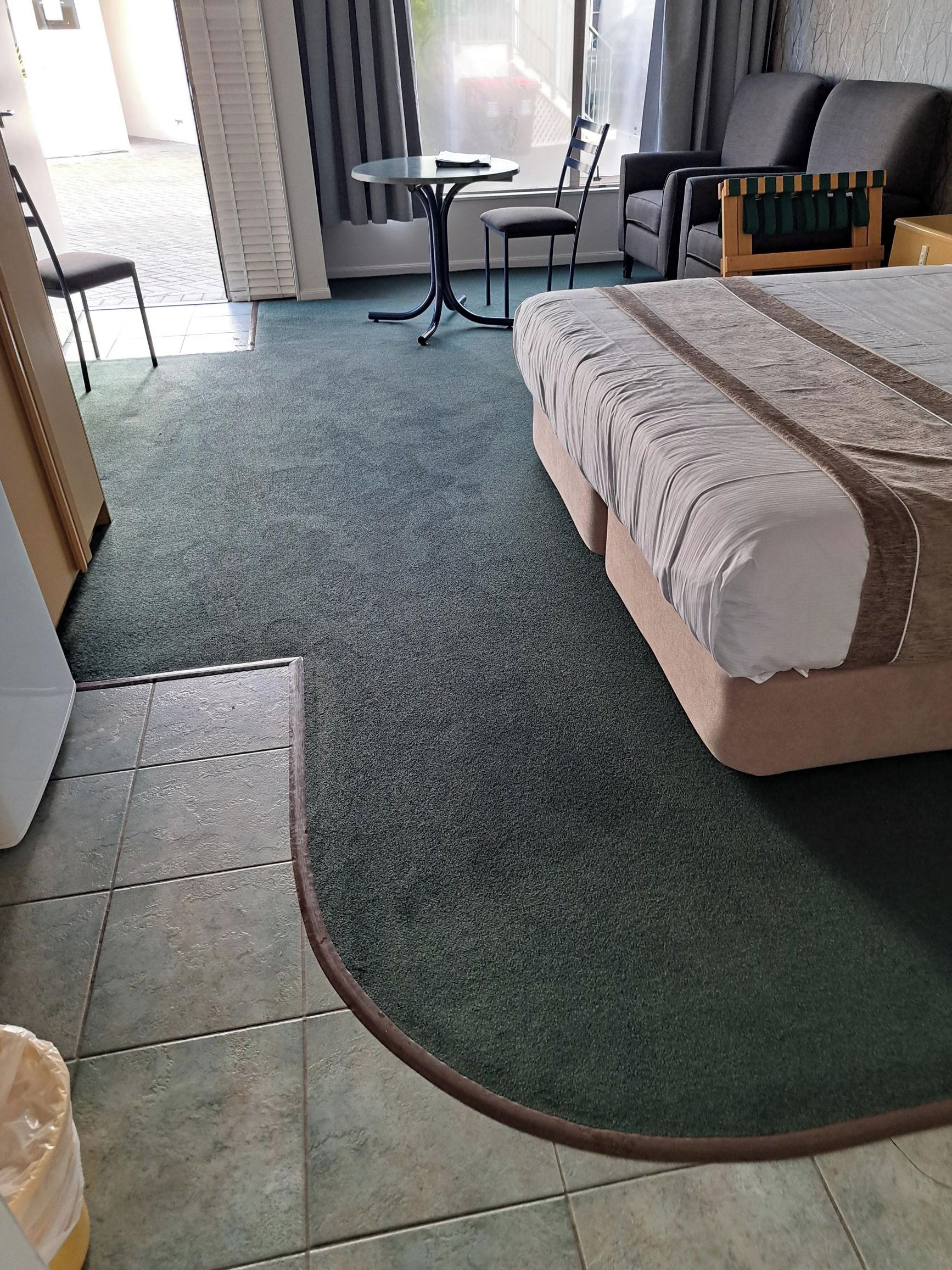Hotellihuone, jossa on sänky, pieni pöytä, tuoli ja sohva.