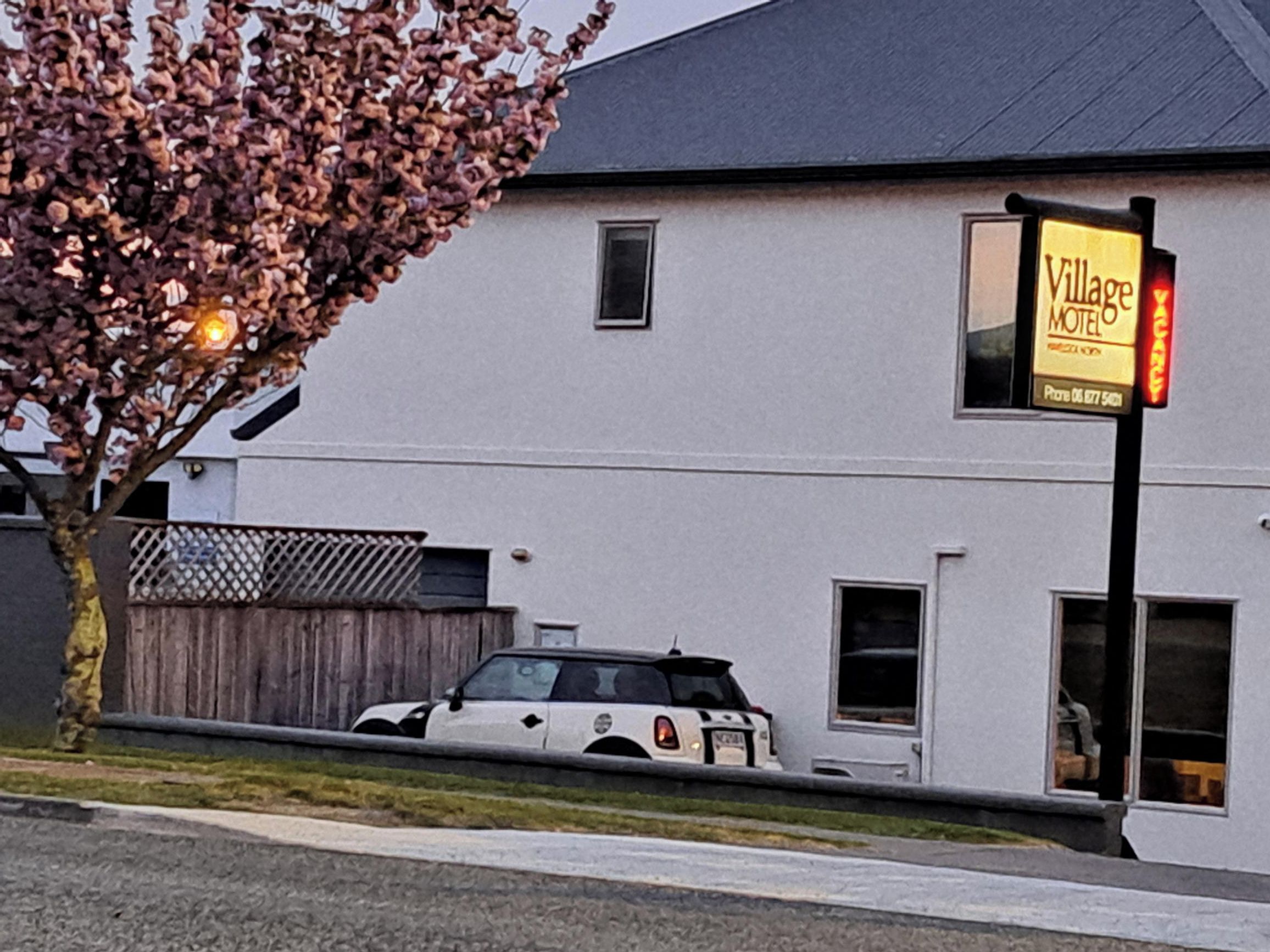 A white building with a sign for 'Village Motel' on the side.