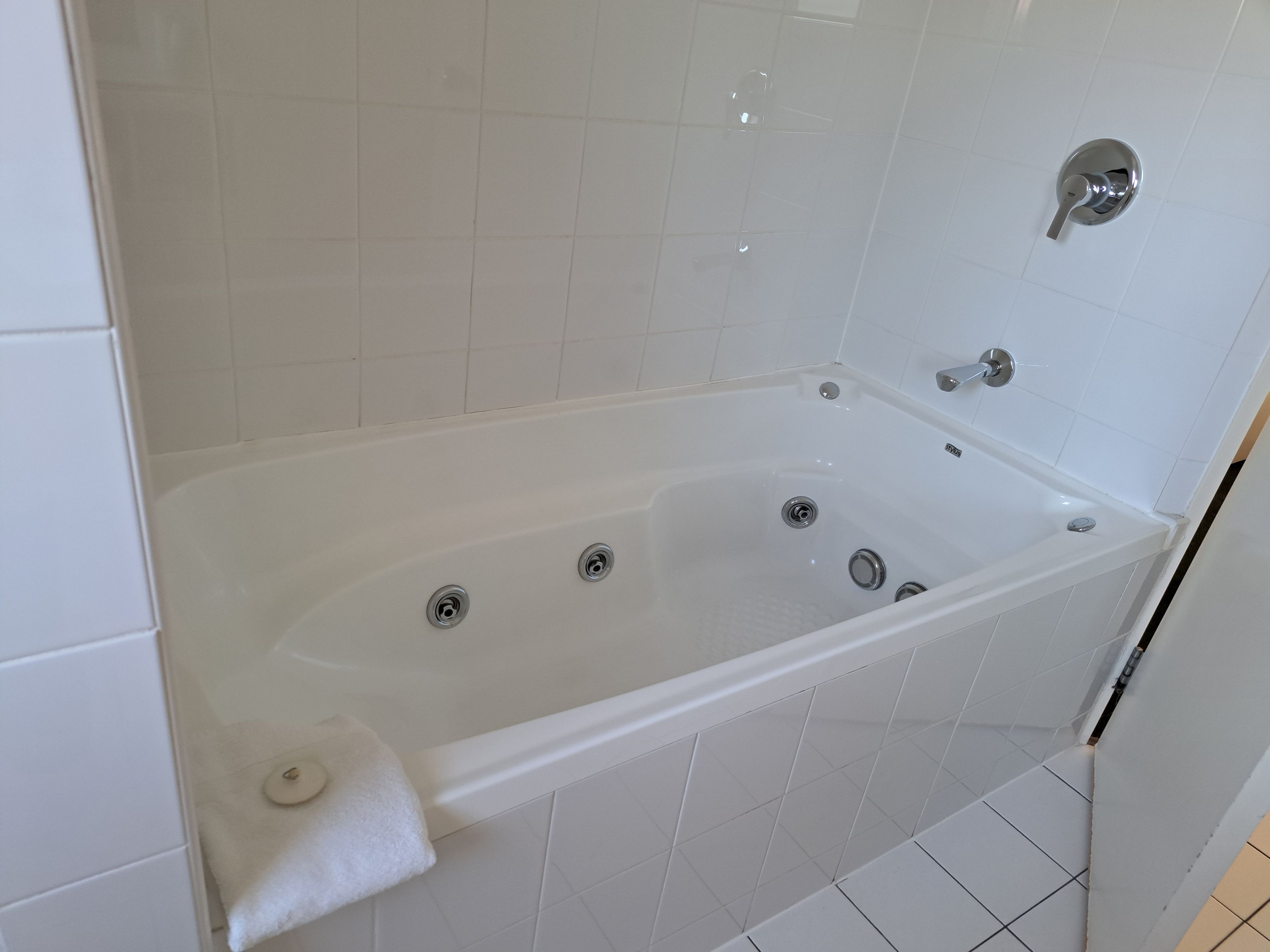 Un baño moderno con una bañera blanca, dos llaves y un cabezal de ducha.