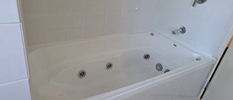 Un baño moderno con una bañera blanca, dos llaves y un cabezal de ducha.