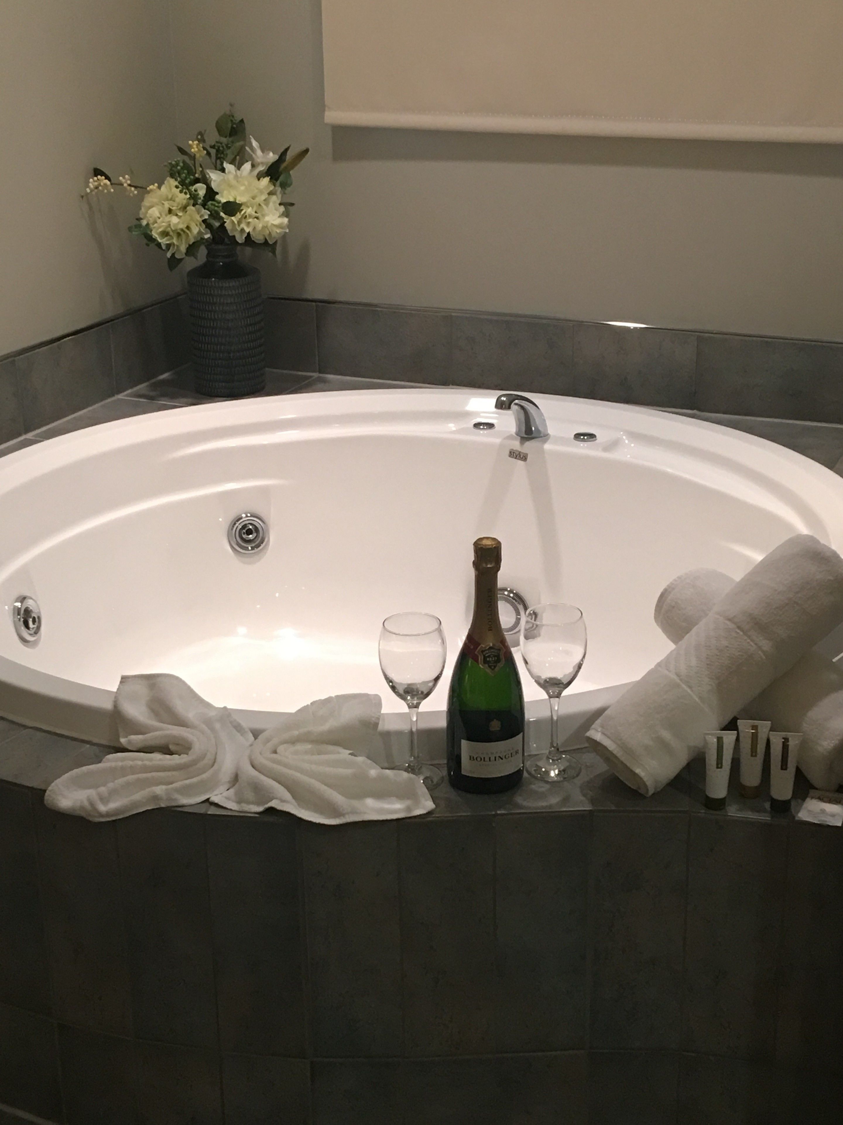 Eine große, runde Badewanne mit einer Champagnerflasche, zwei Weingläsern und einem Handtuch.