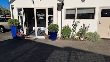 Un edificio con una recepción, un cartel que indica Village Motel, y diversos maceteros con plantas en la entrada.