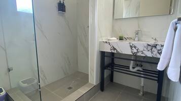 Un baño moderno con ducha acristalada, suelo de mármol y lavamanos con encimera de mármol.
