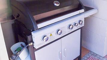 Una griglia a gas portatile con quattro fuochi, un pannello di controllo e un pensile.