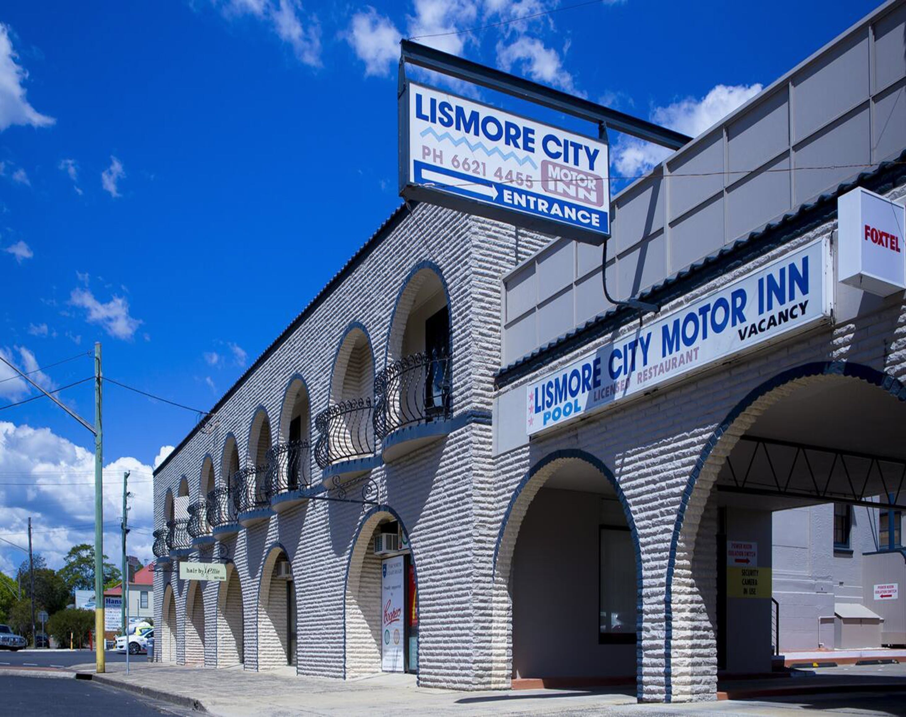 A building with a sign for Lismore City Motor Inn, featuring a brick facade, arched windows, and a visible entrance.