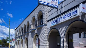 A building with a sign for Lismore City Motor Inn, featuring a brick facade, arched windows, and a visible entrance.