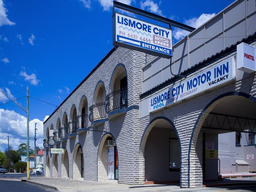 Un edificio con el letrero del Lismore City Motor Inn, que presenta fachada de ladrillo, ventanas arqueadas y una entrada visible.